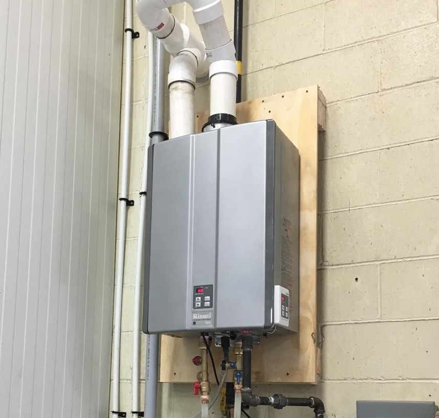 Indoor boiler unit surrounded by insulated red pipes and multiple valves in a mechanical room.