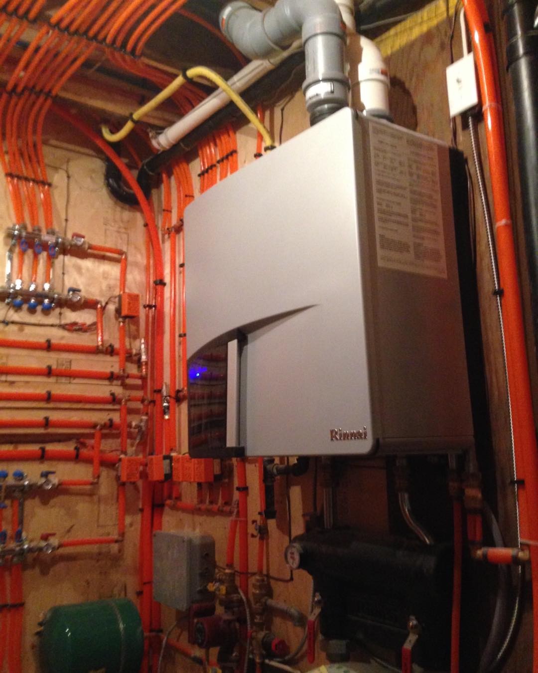 Indoor boiler unit surrounded by insulated red pipes and multiple valves in a mechanical room.